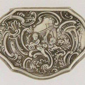 May include: An antique silver box with an ornate design featuring cherubs and scrolling foliage.