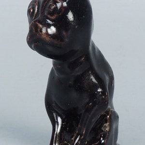 May include: A black ceramic figurine of a cat sitting with its head turned to the side. The cat has a glossy finish and is in a seated position.