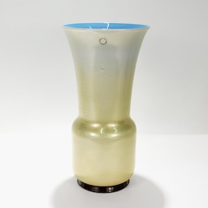May include: A tall, elegant vase with a flared top and a bulbous base. The vase has a light yellow-green hue with a textured surface and a contrasting light blue rim. The base is dark brown.