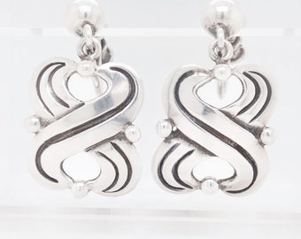 May include: A pair of silver clip-on earrings with a unique, intricate design. The earrings feature a swirling, abstract pattern with a smooth, polished finish.