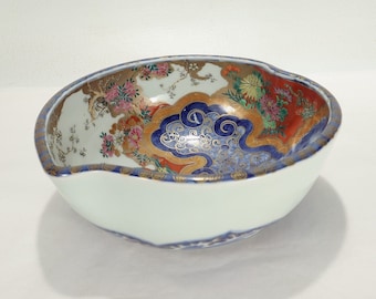 Könnte beinhalten: Eine weiße Keramikschale mit einem blauen, goldenen und roten Blumendesign. Die Schale hat einen gewellten Rand und ist mit einem traditionellen japanischen Muster verziert.