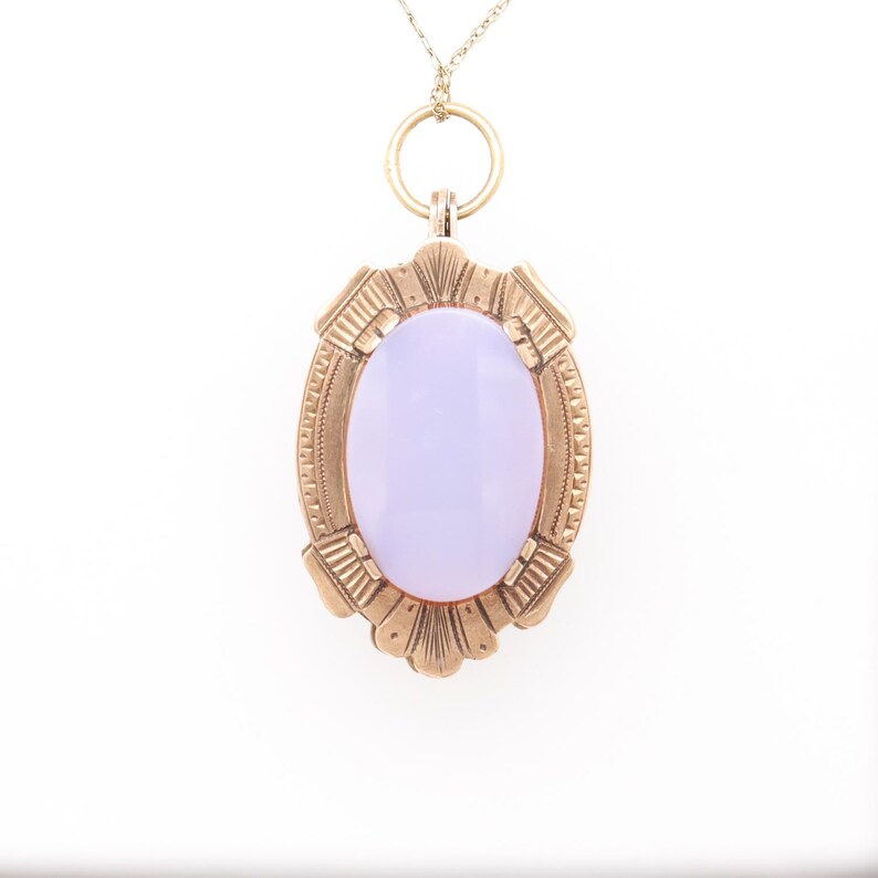 May include: A gold pendant necklace with a lavender oval gemstone set in a detailed gold frame.