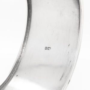Puede incluir: Un brazalete de plata con un sello en el interior.