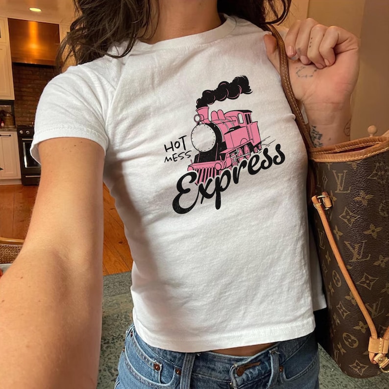 May include: A white cropped t-shirt with a pink cartoon train and the text 'Hot Mess Express' printed on the front.