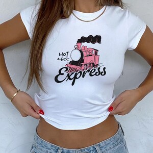 May include: White cropped t-shirt with a pink and black cartoon train graphic and the text "Hot Mess Express".