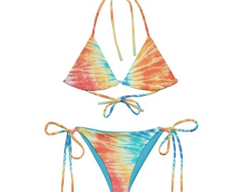 Op de afbeelding: Een tie-dye bikiniset met een driehoekige top en een hoge snit. De bikini is in tinten oranje, geel en blauw.