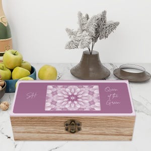 May include: A wooden box with a hinged lid and a metal latch. The lid is decorated with a pink floral design and the text "Queen of the Green". The box is labeled with the initials "SH".
