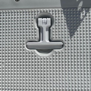 May include: A white plastic surface with a textured pattern of small circles. A white plastic handle with a T-shaped design is attached to the surface.