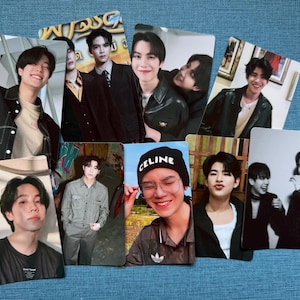 May include: A collection of eight photo cards featuring images of young men in various poses and outfits. The cards display a range of expressions, from smiles to more serious looks. Some cards have text, including the word "CELINE" on a black beanie.