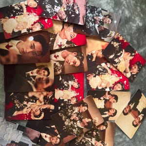 May include: A collection of rectangular photo cards featuring images of people in suits, some with cake on their faces. The cards have a red or brown background. The images show various poses and expressions.
