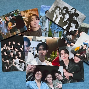May include: A collection of rectangular photo cards featuring various groups of people. The cards display images of people in casual settings, with some cards showing group photos and others featuring individual portraits. The cards are arranged on a blue surface.