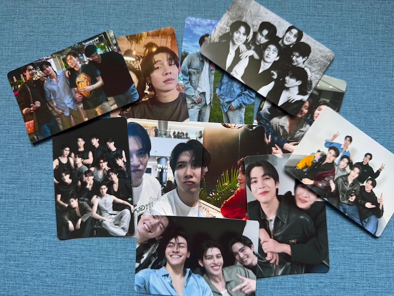 May include: A collection of rectangular photo cards featuring various groups of people. The cards display images of people in casual settings, with some cards showing group photos and others featuring individual portraits. The cards are arranged on a blue surface.