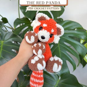 May include: A handmade, orange and white crochet red panda plushie. The plushie has brown and white paws and a striped tail. The text "Tango The Red Panda PDF Crochet Pattern" is displayed above the plushie.