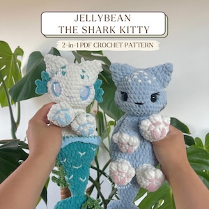 Puede incluir: Dos muñecos de ganchillo hechos a mano con forma de gato tiburón. Uno es blanco con detalles azules y una cola turquesa. El otro es azul claro con almohadillas rosas. El texto de la imagen dice "JELLYBEAN THE SHARK KITTY" y "2-en-1 PDF CROCHET PATTERN".