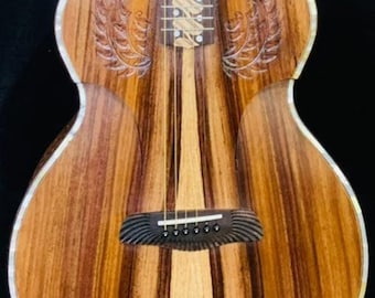 May include: A brown acoustic guitar with a wood grain finish and intricate carvings on the body. The guitar has a gold-colored headstock with a decorative inlay.