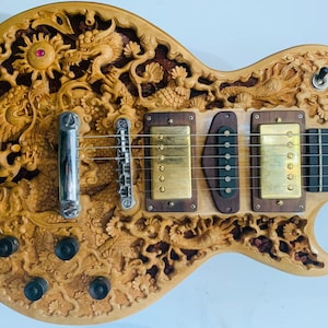 May include: A wooden electric guitar with intricate carvings of dragons and flowers. The guitar has a natural wood finish and gold hardware.