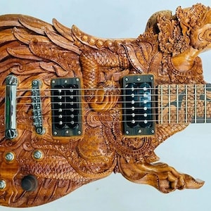 以下が含まれることがあります： 精巧な彫刻が施された、オーダーメイドの木製エレキギター。ギターは、詳細なドラゴンのデザインが特徴で、ボディとヘッドは明るい茶色の木材から彫られています。指板には装飾的な模様があり、ギターには黒いピックアップとシルバーのハードウェアが付いています。