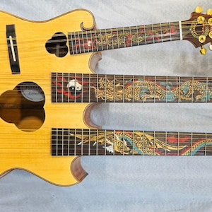 May include: A distinctive multi-neck guitar with a light wood finish. The body is decorated with a detailed green and gold dragon design. The necks feature intricate patterns and gold hardware, combining artistry with musical functionality.