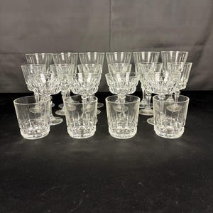 Puede incluir: Una colección de copas y vasos de vidrio transparente con un patrón de corte geométrico y facetado en la parte inferior de los cuencos y las bases. El conjunto incluye recipientes de diversas alturas con estrías verticales y vidrio grueso.