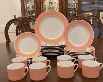 May include: A set of pink and white china dinnerware with a delicate pink trim. The set includes dinner plates, salad plates, and teacups.
