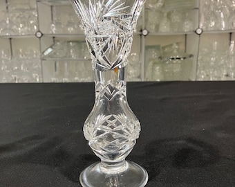 May include: A clear glass vase with a cut crystal design. The vase has a wide mouth and a narrow base.