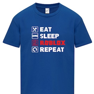 May include: A royal blue t-shirt with a white graphic that says "Eat Sleep Roblox Repeat" with a tick next to each word. The word "Roblox" is in red.