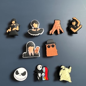 May include: Nine colorful character charms featuring characters from the Nightmare Before Christmas movie. The charms are made of a rubber-like material and are approximately 1 inch in size. The characters include Jack Skellington, Sally, Oogie Boogie, the Mayor, and more.