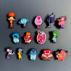 Puede incluir: Un conjunto de 15 dijes de personajes coloridos con personajes de la película animada Inside Out. Los personajes incluyen Alegría, Tristeza, Ira, Miedo, Desagrado, Bing Bong y otros. Los dijes están hechos de goma y están diseñados para ser unidos a zapatos u otros accesorios.