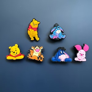 May include: Six colourful cartoon character shoe charms featuring Winnie the Pooh, Tigger, Eeyore, Piglet, and two versions of Eeyore.