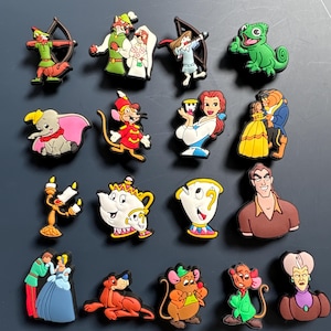 Peut inclure: Un ensemble de 16 breloques colorées de personnages Disney mettant en scène des personnages comme Robin des Bois, Belle et la Bête. Les breloques sont en caoutchouc et sont parfaites pour ajouter une touche de magie Disney à vos chaussures, sacs ou autres accessoires.