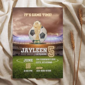 Op de afbeelding: Een uitnodigingskaart met voetbalthema met een stadionachtergrond, een voetbal en een trofee. De kaart leest "IT'S GAME TIME!" en bevat details voor een verjaardagsfeestje.