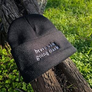 May include: Black beanie with white embroidered text that reads "bravo six going dark".