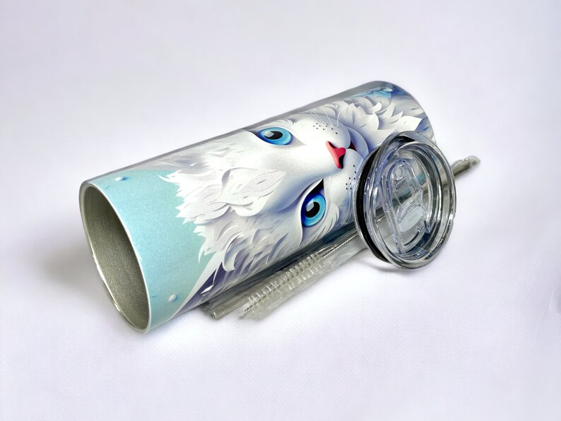 Edelstahl-Tumbler 590 ml mit weißer Katze und blauen Blumen, doppelwandig isoliert, inklusive Deckel und Edelstahl-Strohhalm. Hält Getränke 12 Stunden kalt oder 6 Stunden heiß. Hochwertig sublimiert, langlebig und wiederverwendbar. Perfektes Geschenk für Katzenliebhaber und Tierfreunde.