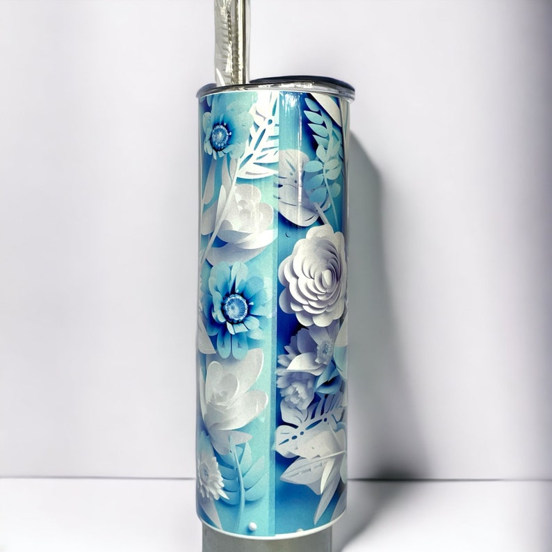 Edelstahl-Tumbler 590 ml mit weißer Katze und blauen Blumen, doppelwandig isoliert, inklusive Deckel und Edelstahl-Strohhalm. Hält Getränke 12 Stunden kalt oder 6 Stunden heiß. Hochwertig sublimiert, langlebig und wiederverwendbar. Perfektes Geschenk für Katzenliebhaber und Tierfreunde.
