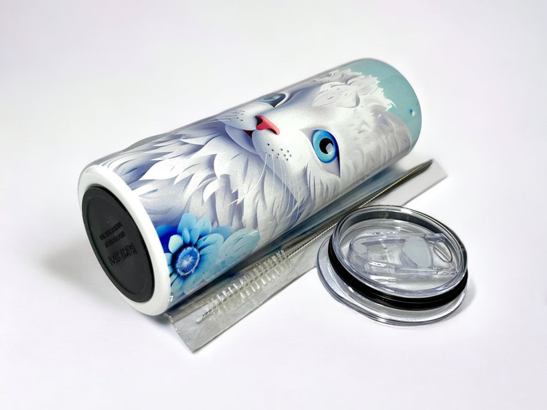Edelstahl-Tumbler 590 ml mit weißer Katze und blauen Blumen, doppelwandig isoliert, inklusive Deckel und Edelstahl-Strohhalm. Hält Getränke 12 Stunden kalt oder 6 Stunden heiß. Hochwertig sublimiert, langlebig und wiederverwendbar. Perfektes Geschenk für Katzenliebhaber und Tierfreunde.