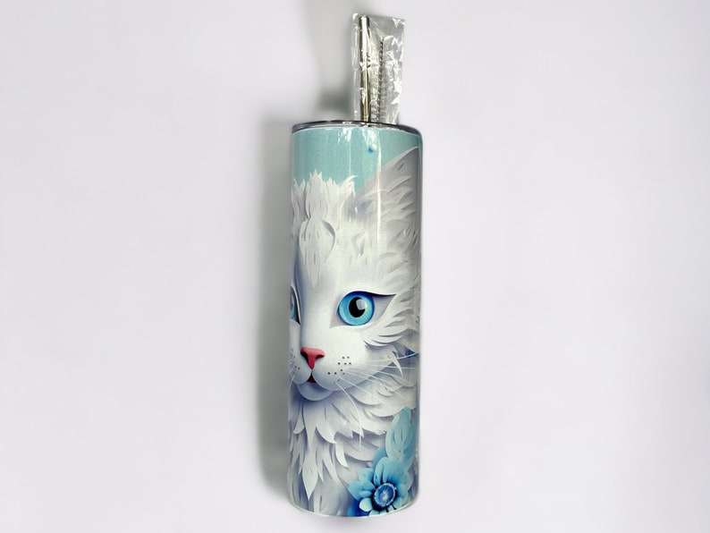 Edelstahl-Tumbler 590 ml mit weißer Katze und blauen Blumen, doppelwandig isoliert, inklusive Deckel und Edelstahl-Strohhalm. Hält Getränke 12 Stunden kalt oder 6 Stunden heiß. Hochwertig sublimiert, langlebig und wiederverwendbar. Perfektes Geschenk für Katzenliebhaber und Tierfreunde.