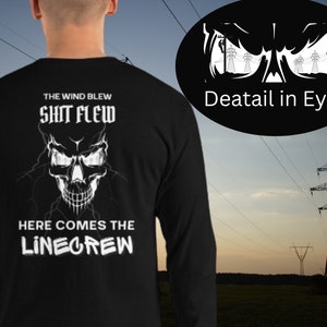 Può includere: Maglietta nera a maniche lunghe con un grafico di teschio bianco e il testo "The wind blew, shit flew, here comes the linecrew". Il teschio ha fulmini che escono dai suoi occhi. Il testo "Deatail in Eyes" è in un cerchio sopra la maglietta.