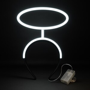 May include: A glowing white halo headband with a battery pack. The halo is composed of a circular top and a curved base connected by a vertical bar. The headband is black. The battery pack is clear and connected by a thin wire.