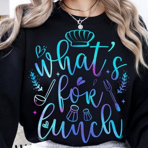 Może przedstawiać: Czarna bluza z napisem "What's for lunch" w gradientowym kolorze niebieskim, fioletowym i różowym. Projekt zawiera czapkę kucharską, łyżkę, widelec, solniczki i pieprzniczki oraz elementy dekoracyjne.