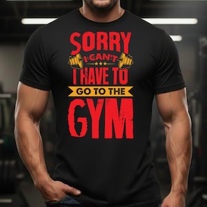 Może przedstawiać: Czarna koszulka z napisem "SORRY I CAN'T I HAVE TO GO TO THE GYM" w kolorze czerwonym i żółtym. Koszulka posiada grafikę sztangi. Zdjęcie przedstawia osobę noszącą koszulkę.