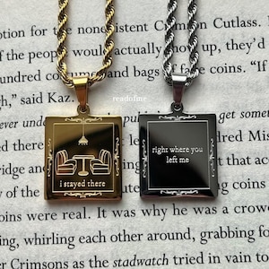 Puede incluir: Dos collares de oro y plata con colgantes cuadrados. El colgante de oro tiene una pequeña ilustración de una mesa con sillas y el texto "I stayed there". El colgante de plata tiene el texto "right where you left me".