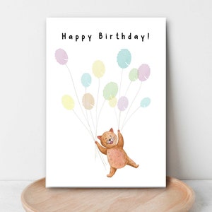 K&ouml;nnte beinhalten: Eine Geburtstagskarte mit einer braunen Katze, die an bunten Luftballons festh&auml;lt. Die Ballons sind aus Fingerabdruckmustern gefertigt und die Karte lautet "Happy Birthday!"