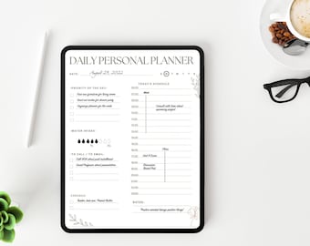 Peut inclure: Un planificateur personnel quotidien noir et blanc sur une tablette blanche avec un motif floral. Le planificateur comprend des sections pour la date, la priorité du jour, l'horaire du jour, l'apport en eau, les appels/les e-mails, les courses et les notes. La date est le 29 août 2022.