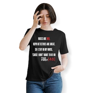 May include: Black t-shirt with the text "ROSES ARE RED, NCPD DETECTIVES ARE GREAT, SO I STAY IN MY HOUSE, 'CAUSE I DON'T WANT TO BE ON THE FIRST [48]" in red and white. The shirt is a crew neck.