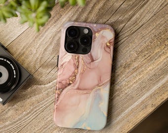 May include: A smartphone case with a marble design in shades of pink, gold, and light blue. The case has a glossy finish and a camera cutout. The phone case is on a wooden surface.