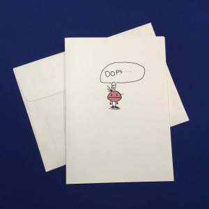 May include: A white card with a hand-drawn cartoon of a red character with a thought bubble above its head that says "OOPS..."