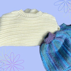 May include: Three handmade crochet sweaters in the image. One is a cream color, and the other two are blue with purple and teal stripes. The sweaters have a ribbed texture and a crew neck design. The background is a light purple with flower outlines.
