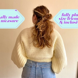 May include: A cream-colored, cropped sweater with long, voluminous sleeves. The sweater is made of a chunky knit material. Text in the image reads "totally made to measure" and "fully plus size friendly & inclusive!"