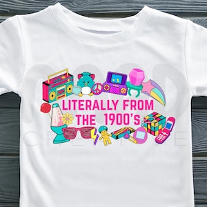May include: White t-shirt with a colorful graphic of 1990s icons, including a boombox, Rubik's Cube, and a cell phone. The text "Literally From The 1900's" is in pink and yellow. The shirt has short sleeves.
