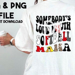 Puede incluir: Camiseta blanca con el texto "Somebody's Loud Mouth Softball Mama" en letras coloridas de estilo retro. Las letras están decoradas con gráficos de temática de softbol, incluyendo una pelota de béisbol, un corazón y un estampado de leopardo.